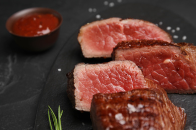 Photo of Delicious sliced beef tenderloin on black table, closeup
