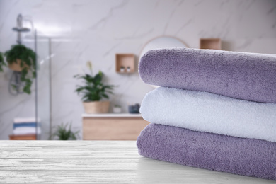 Image of Stack of fresh towels on white wooden table in bathroom. Space for text