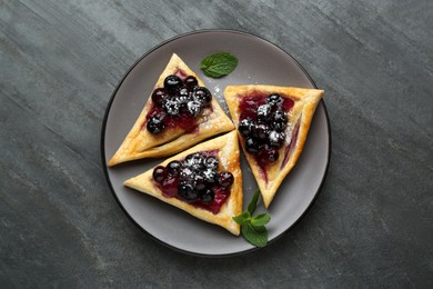 Fresh tasty puff pastry with sugar powder, jam, sweet berries and mint on grey table, top view