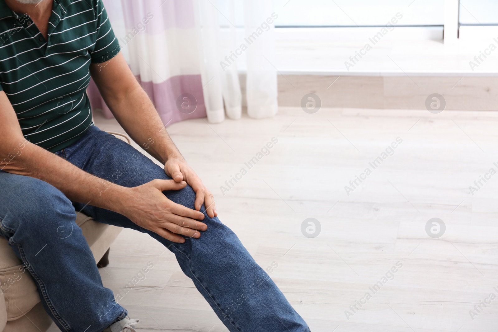 Photo of Senior man suffering from knee pain at home, closeup. Space for text