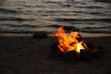 Photo of Beautiful bonfire with burning firewood on beach in evening