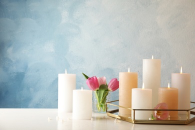 Composition with burning candles on table against color background. Space for text