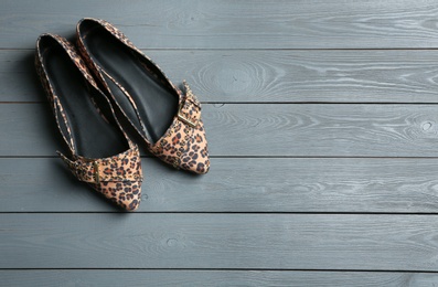 Photo of Female shoes with leopard print on wooden background, top view. Space for text