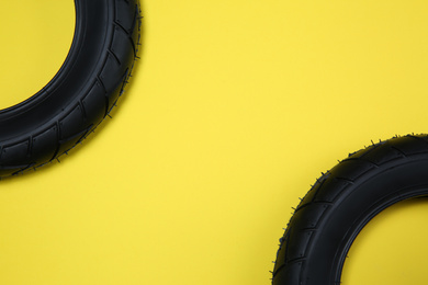 Bicycle tires on yellow background, flat lay. Space for text