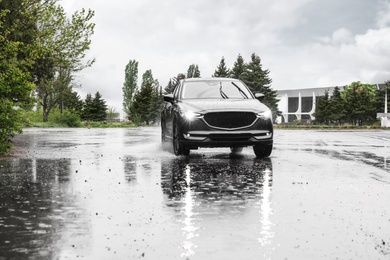 Photo of Modern car driving outdoors on rainy day