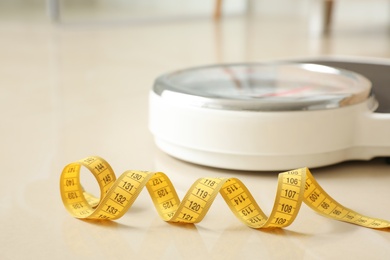 Photo of Scales and measuring tape on floor in bathroom. Overweight problem