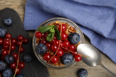 Photo of Delicious yogurt parfait with fresh berries and mint on wooden table, flat lay