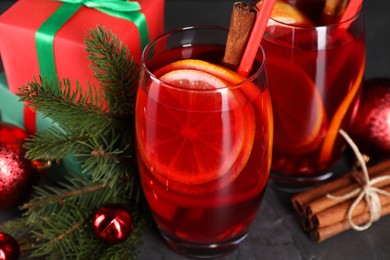 Delicious Sangria drink in glasses and Christmas decorations on dark textured table, closeup