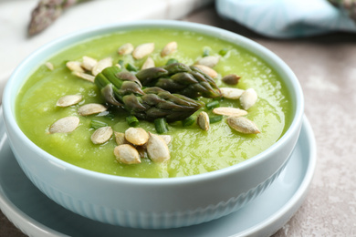 Photo of Delicious asparagus soup in bowl on grey marble table, closeup