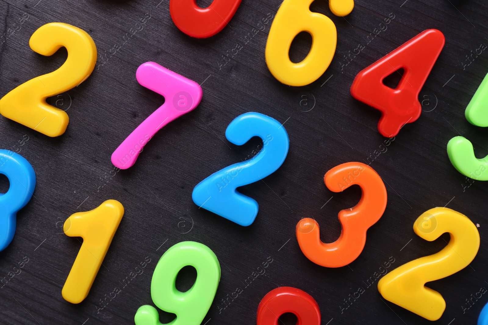 Photo of Colorful numbers on dark wooden school desk, flat lay