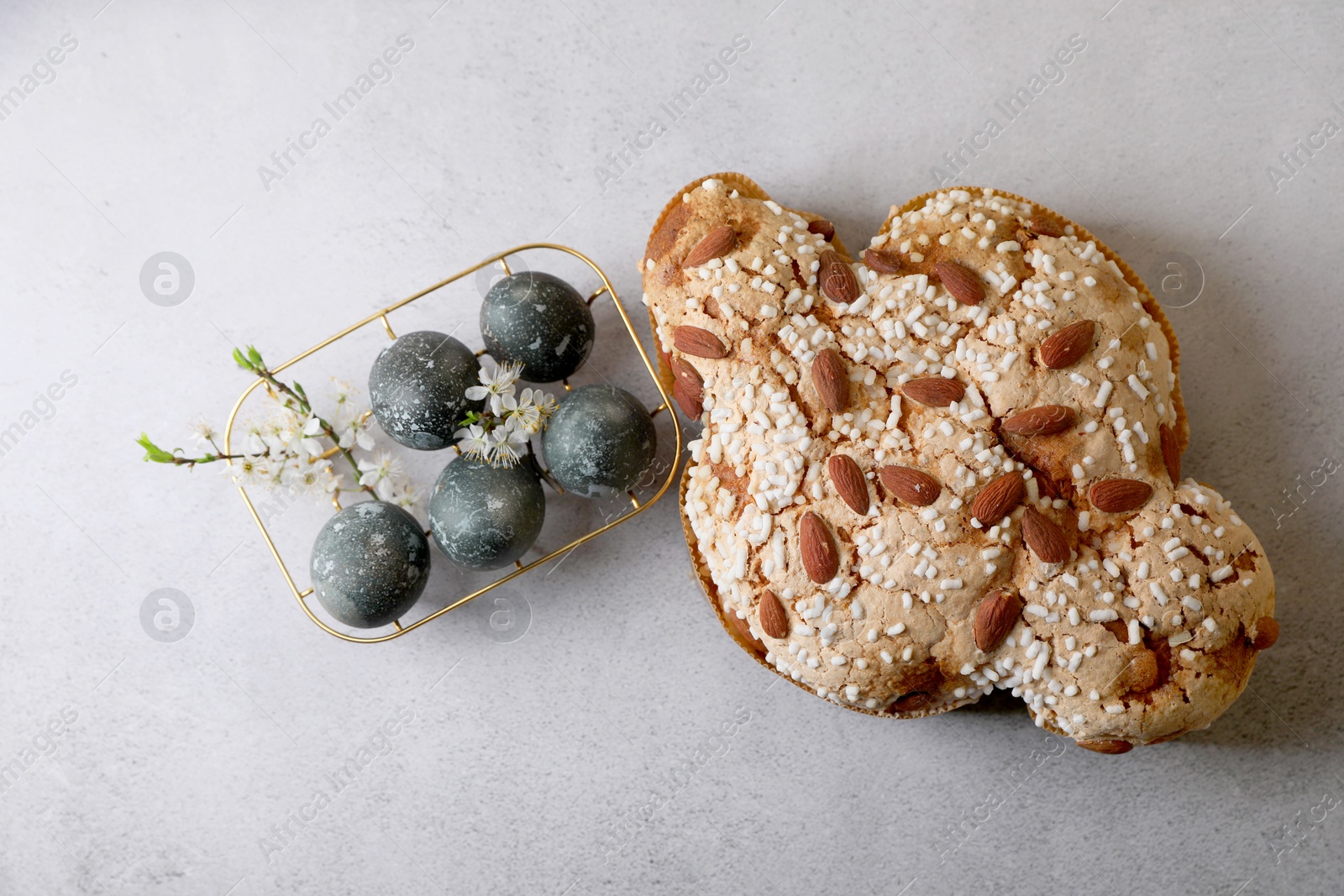 Photo of Delicious Italian Easter dove cake (Colomba di Pasqua) and decorated eggs on grey table, flat lay