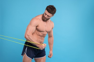 Photo of Young man exercising with elastic resistance band on light blue background. Space for text