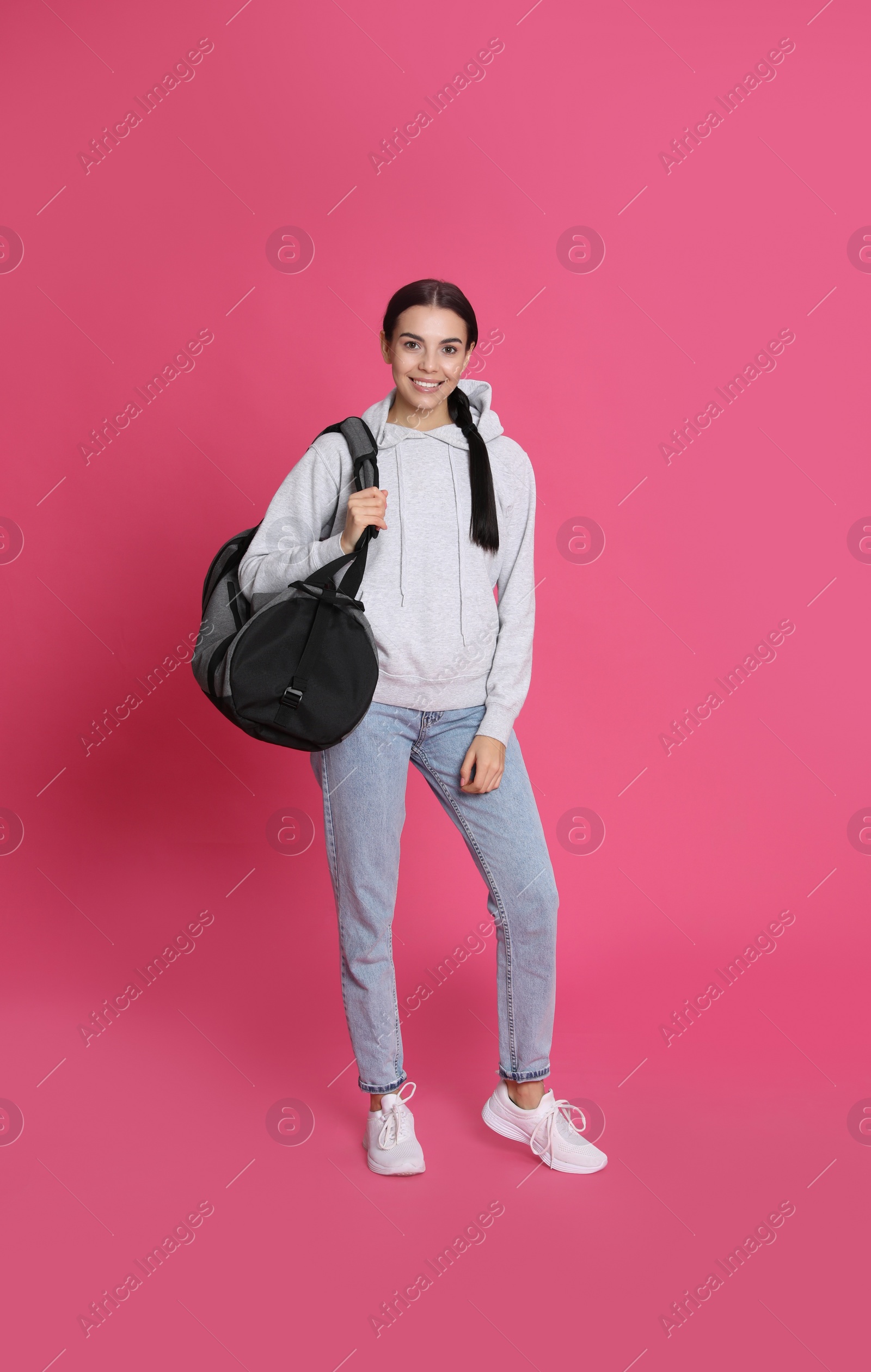 Photo of Beautiful woman with sports bag on pink background