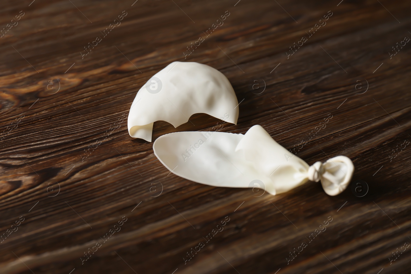 Photo of Popped white latex balloon on wooden background