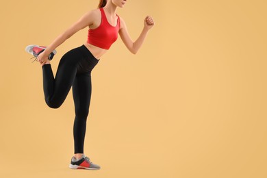 Young woman in sportswear doing exercises on beige background, closeup. Space for text