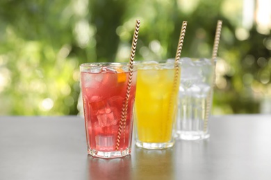 Photo of Delicious refreshing drinks in glasses on grey table outdoors