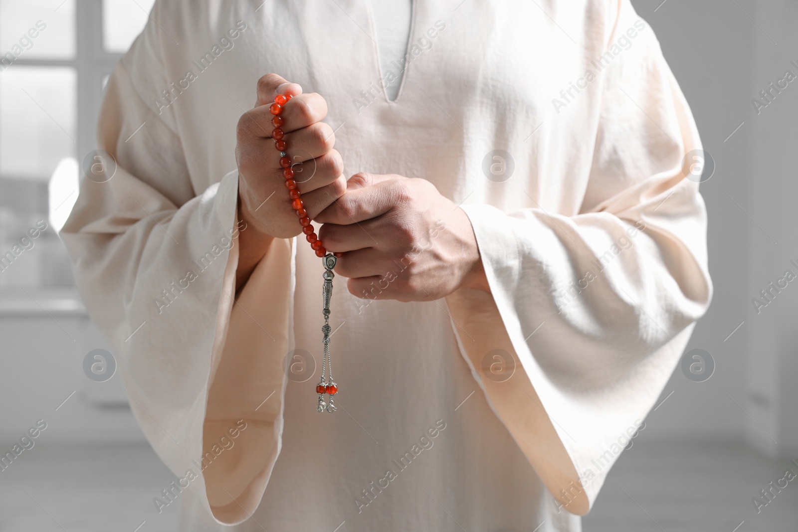 Photo of Muslim man with misbaha indoors, closeup view