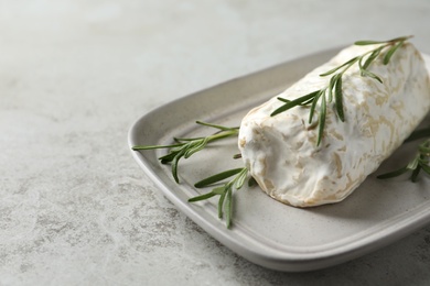 Photo of Delicious fresh goat cheese with rosemary on light grey table