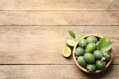 Photo of Flat lay composition with fresh green feijoa fruits on wooden table, space for text