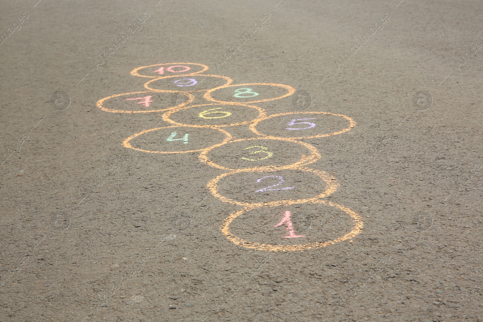 Photo of Hopscotch drawn with colorful chalk on asphalt outdoors, closeup