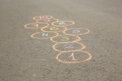 Hopscotch drawn with colorful chalk on asphalt outdoors, closeup