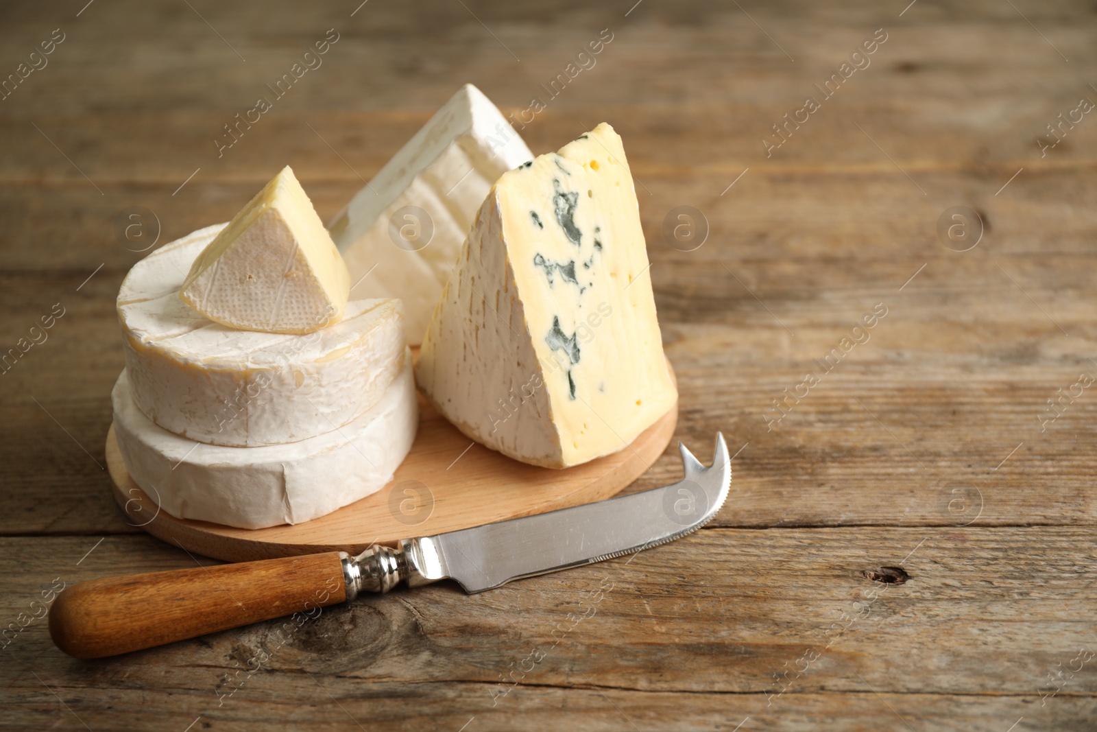 Photo of Different types of cheese and knife on wooden table