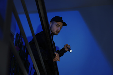 Male security guard with flashlight on stairs in darkness