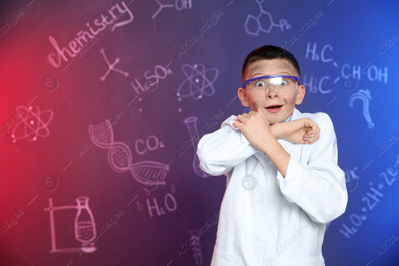 Photo of Emotional pupil shielding himself against blackboard with written chemistry formulas. Space for text