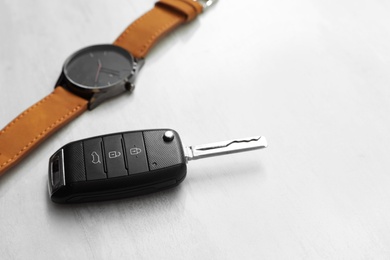 Wristwatch and car key on light background