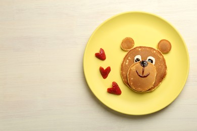 Photo of Creative serving for kids. Plate with strawberries, cute bear made of pancakes on light wooden table, top view Space for text