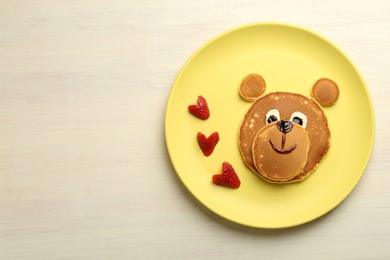 Creative serving for kids. Plate with strawberries, cute bear made of pancakes on light wooden table, top view Space for text