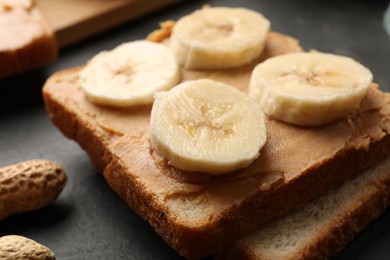 Photo of Tasty peanut butter sandwich and sliced banana on table, closeup