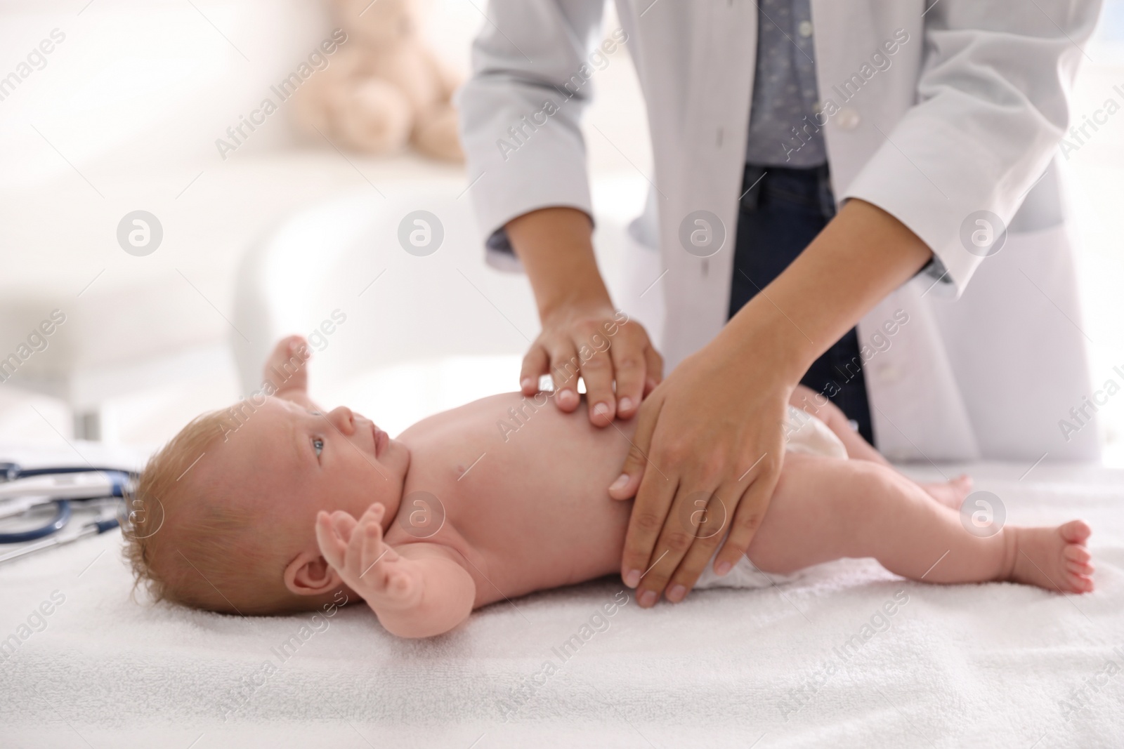 Photo of Doctor examining cute baby indoors, closeup. Health care