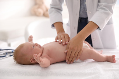 Doctor examining cute baby indoors, closeup. Health care