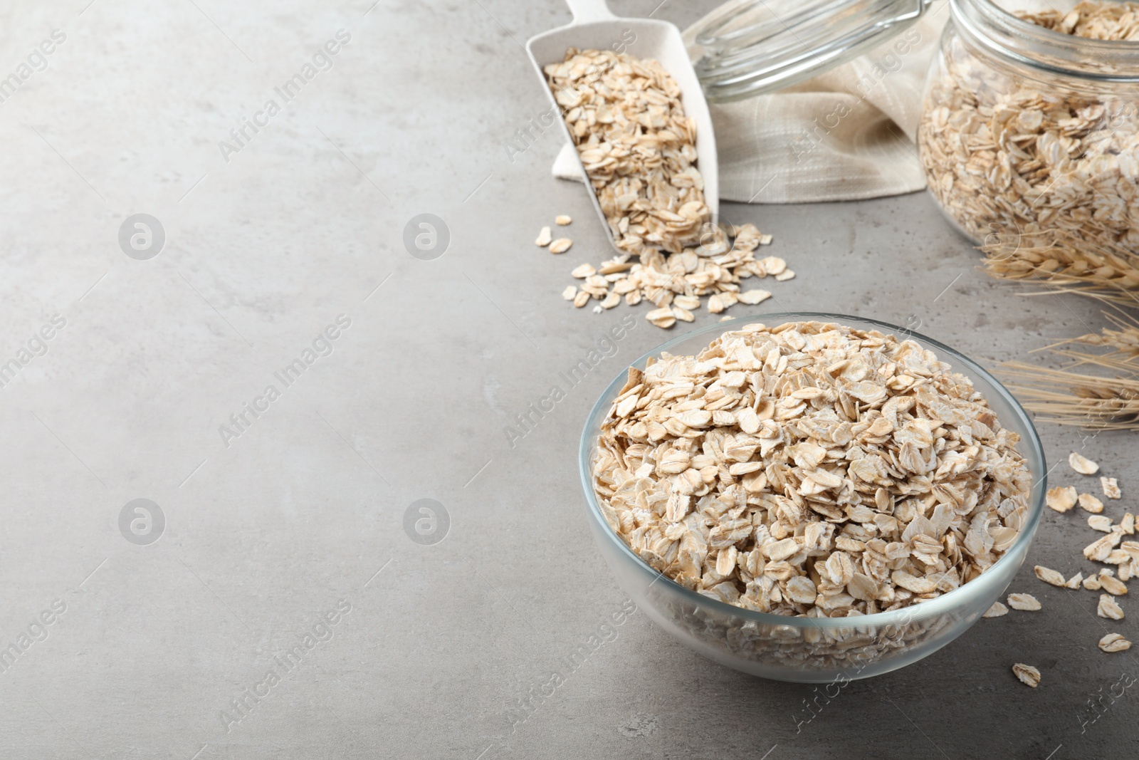 Photo of Glass bowl with oatmeal on grey table. Space for text