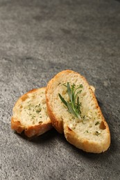 Photo of Tasty baguette with garlic, rosemary and dill on grey textured table