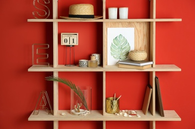 Photo of Stylish wooden shelves with decorative elements on red wall