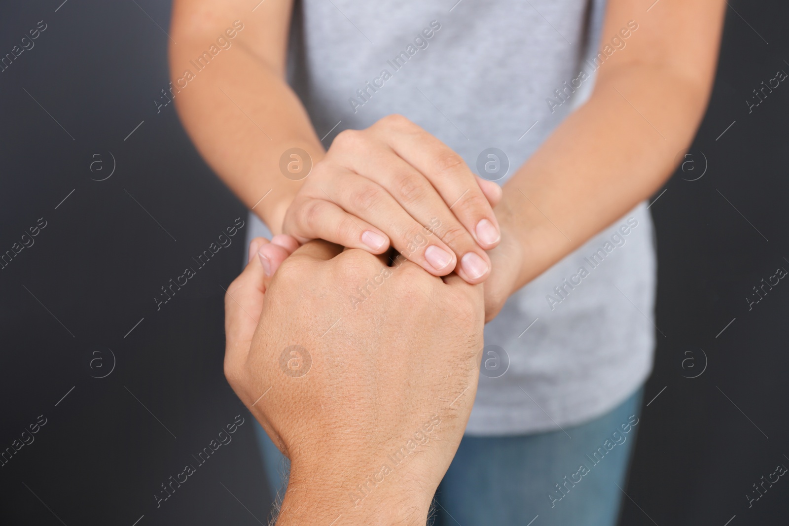 Photo of Woman holding man's hand on gray background, closeup. Concept of support and help