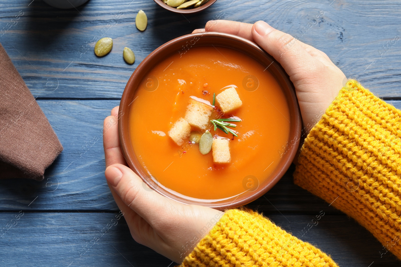 Photo of Woman with bowl of tasty sweet potato soup at table, top view