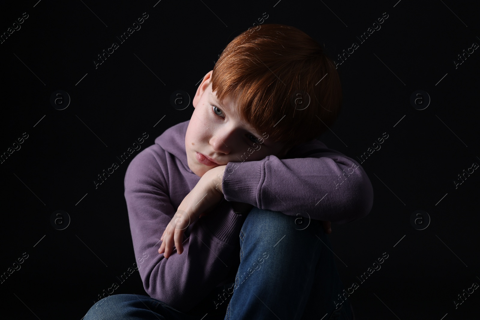 Photo of Portrait of sad little boy on black background