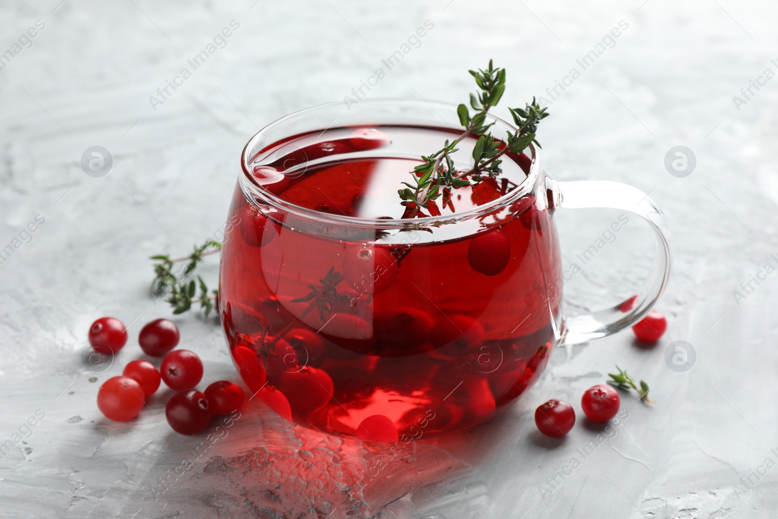 Photo of Delicious cranberry tea with thyme and berries on grey table, closeup