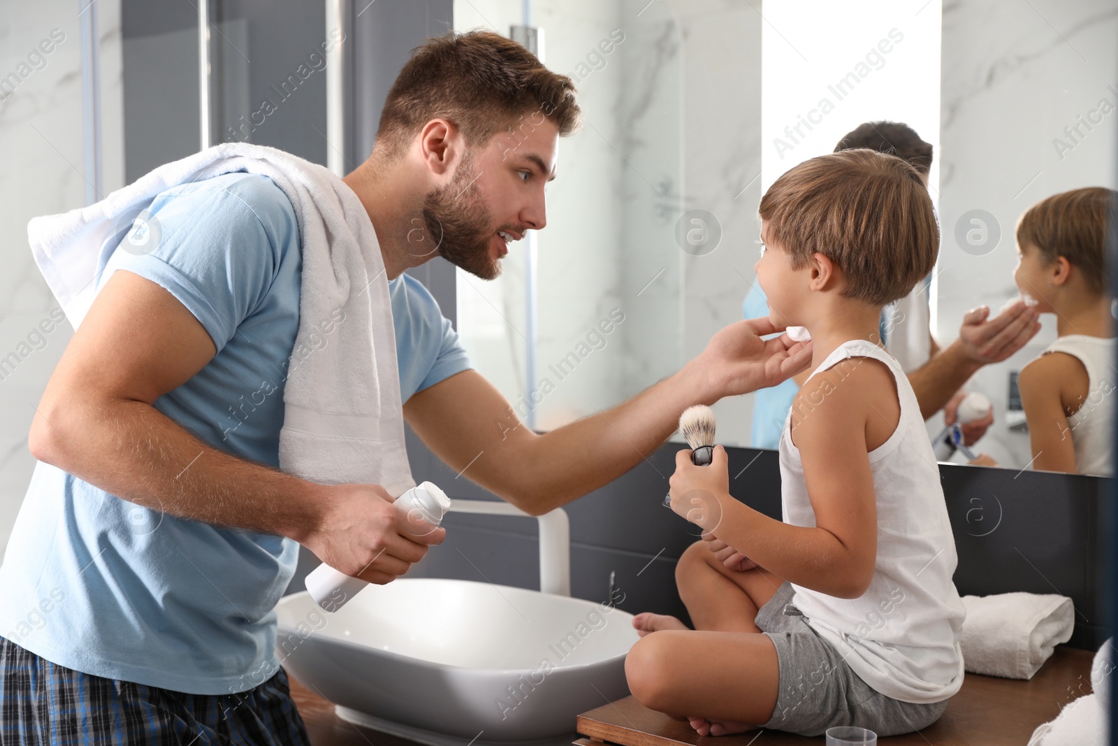 Photo of Dad applying shaving foam onto son's face in bathroom