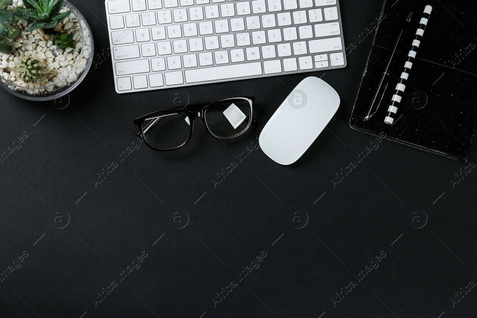 Photo of Flat lay composition with computer keyboard and notebook on black background, space for text. Graphic designer's workplace