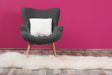 Comfortable armchair with white cushion and rug against color wall