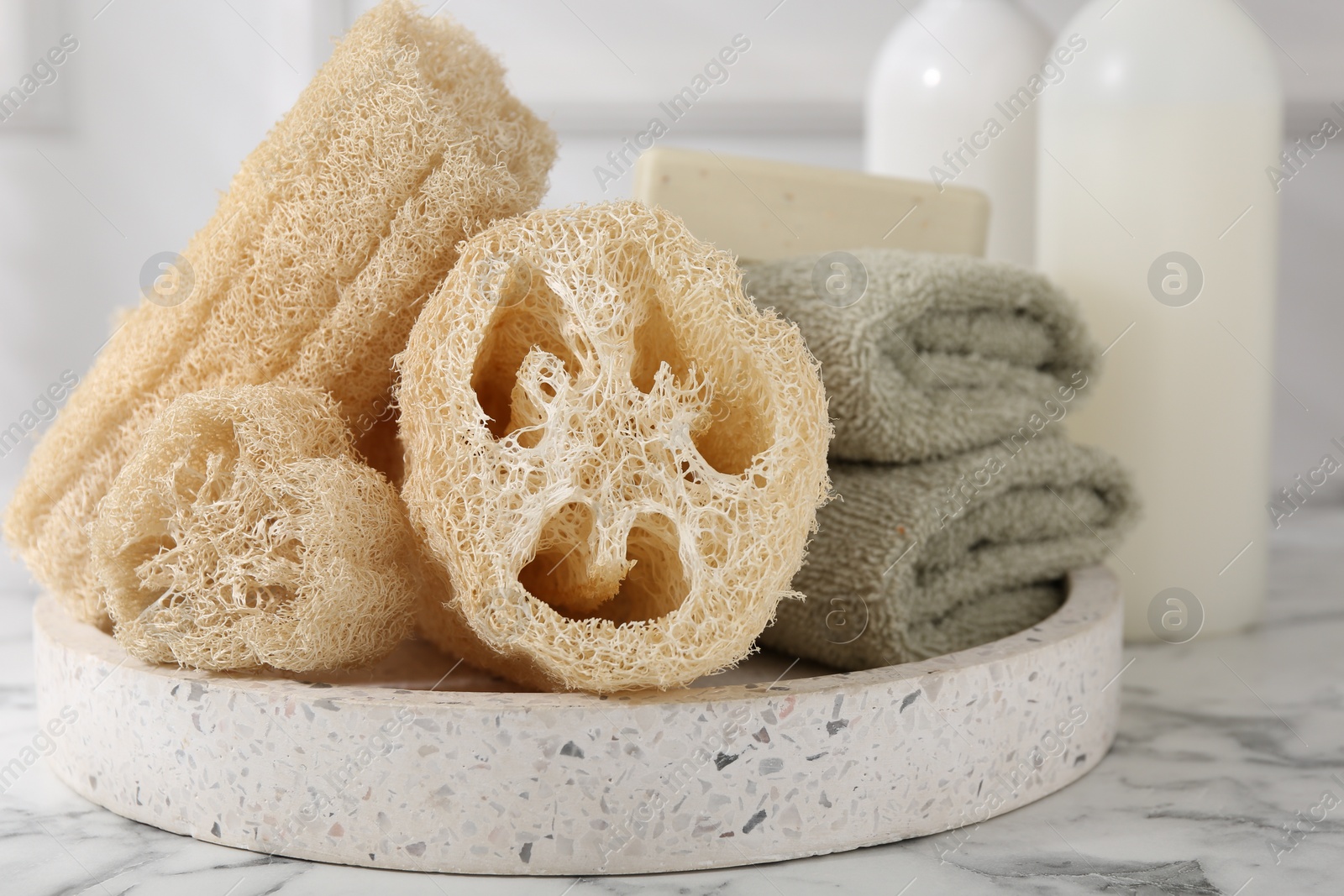 Photo of Loofah sponges, towels and soap on white marble table