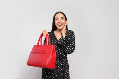 Emotional woman with stylish bag on white background,