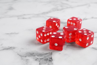 Photo of Many red game dices on white marble table. Space for text