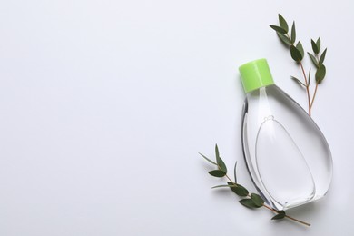 Photo of Bottle of baby oil and leaves on white background, flat lay. Space for text