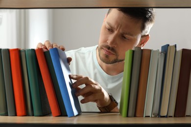 Photo of Man searching for book on shelf in library