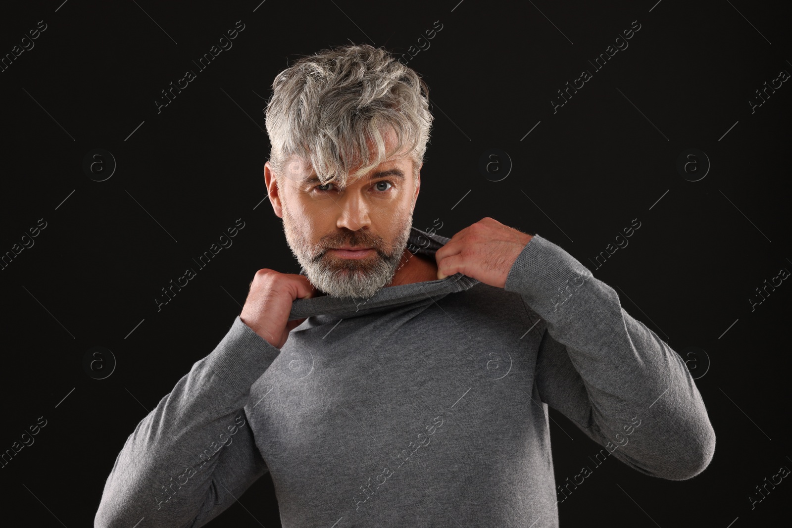 Photo of Portrait of confident man with beautiful hairstyle on black background